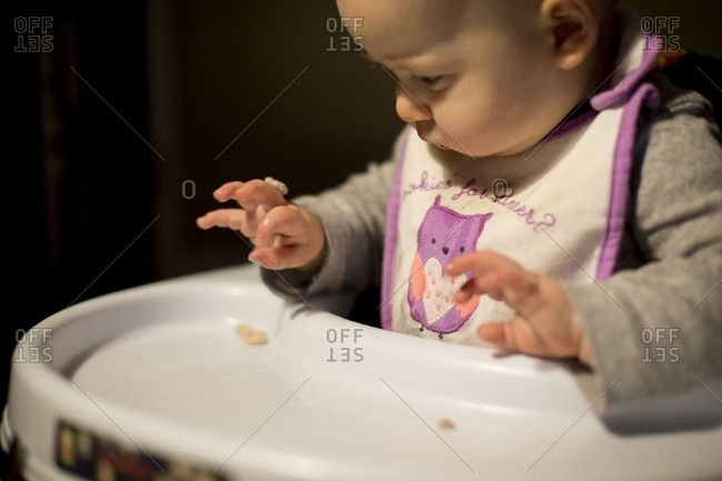 Baby playing with cereal in a high chair