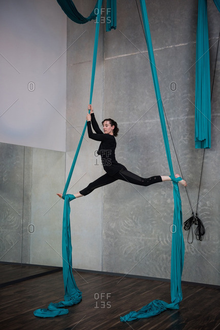 Gymnast exercising on blue fabric rope stock photo - OFFSET