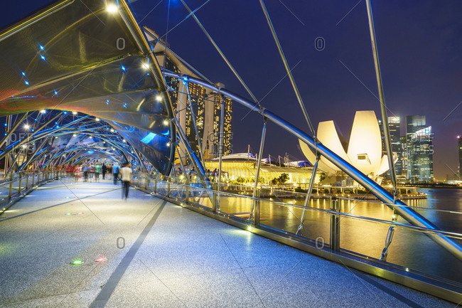 February 20, 2016: People strolling on the Helix Bridge towards the Marina Bay Sands and ArtScience Museum at night, Marina Bay, Singapore, Southeast Asia, Asia