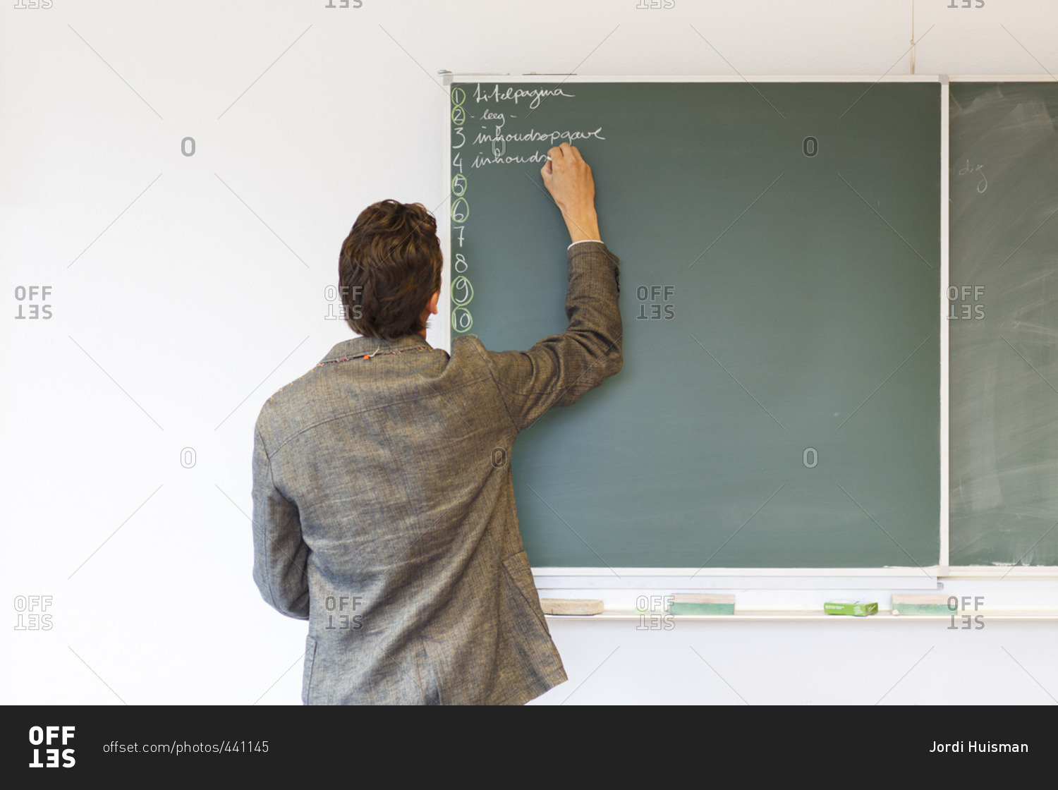 A biology teacher writing on a chalk board during a class