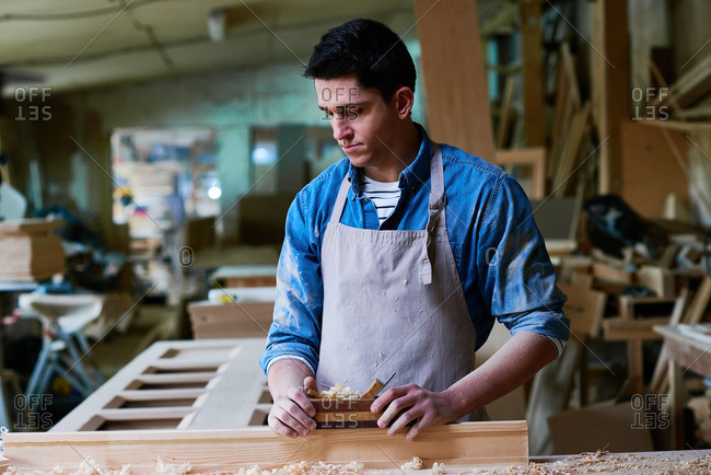 Craftsman using a wood plane in his workshop