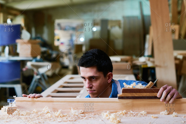 Craftsman inspecting his work with a wood plane in his workshop