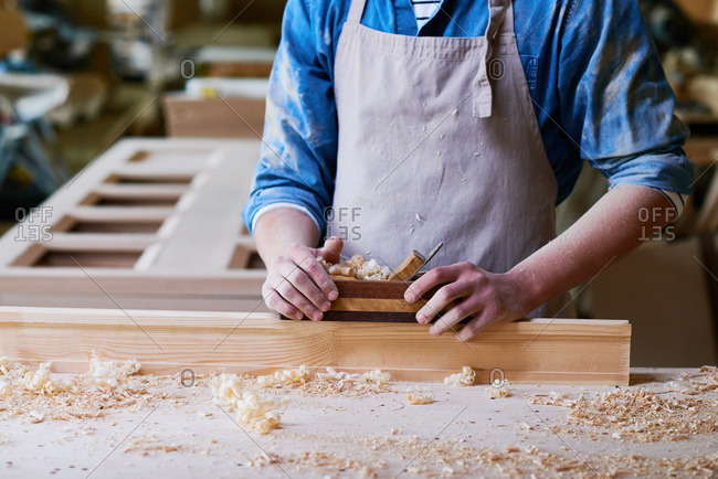 Close up of a craftsman using a wood plane in his workshop