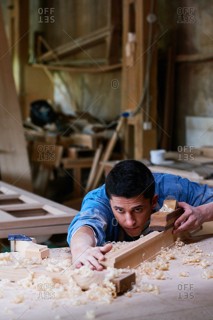 Craftsman checking out his work with a wood plane in his workshop
