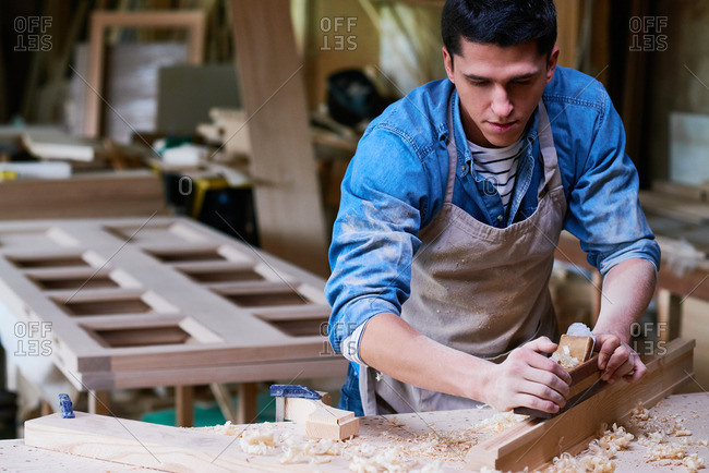 Craftsman smoothing a piece of lumber in his workshop