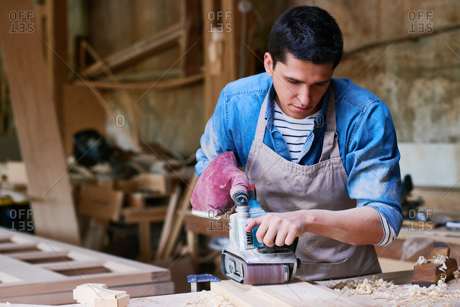 Craftsman using a belt sander in his workshop