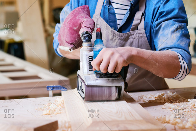 Close up of man using a belt sander in his workshop