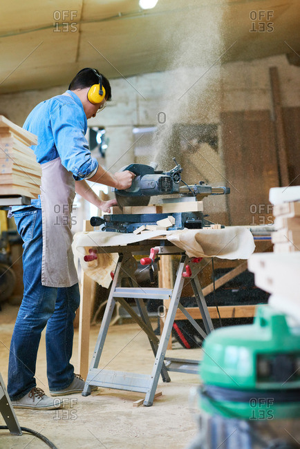 Man using a miter saw to saw wood in his workshop