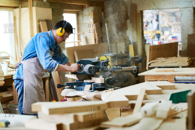Man using a miter saw to cut wood in his workshop