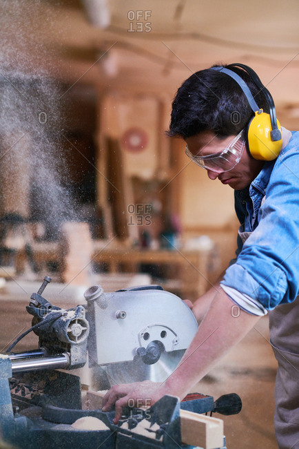 Man cutting wood with a miter saw in his workshop