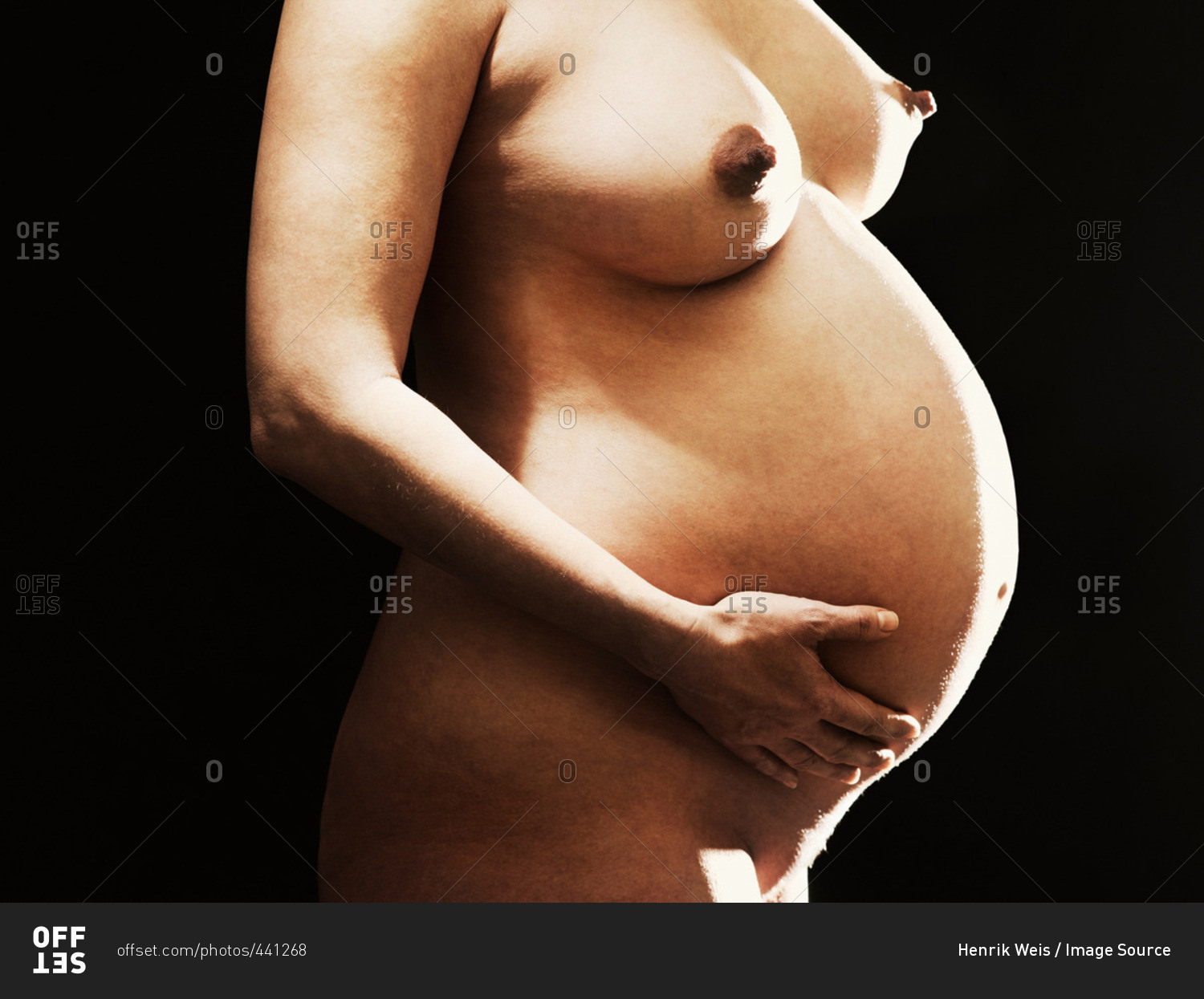 Nude pregnant woman holding her belly stock photo picture