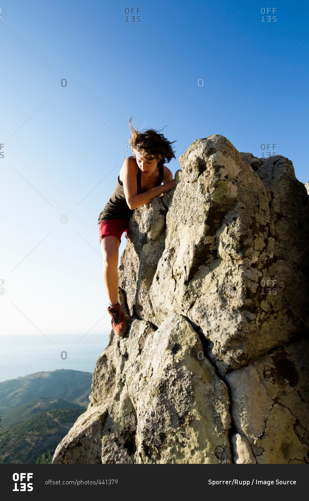 Hiker climbing rocks on hill