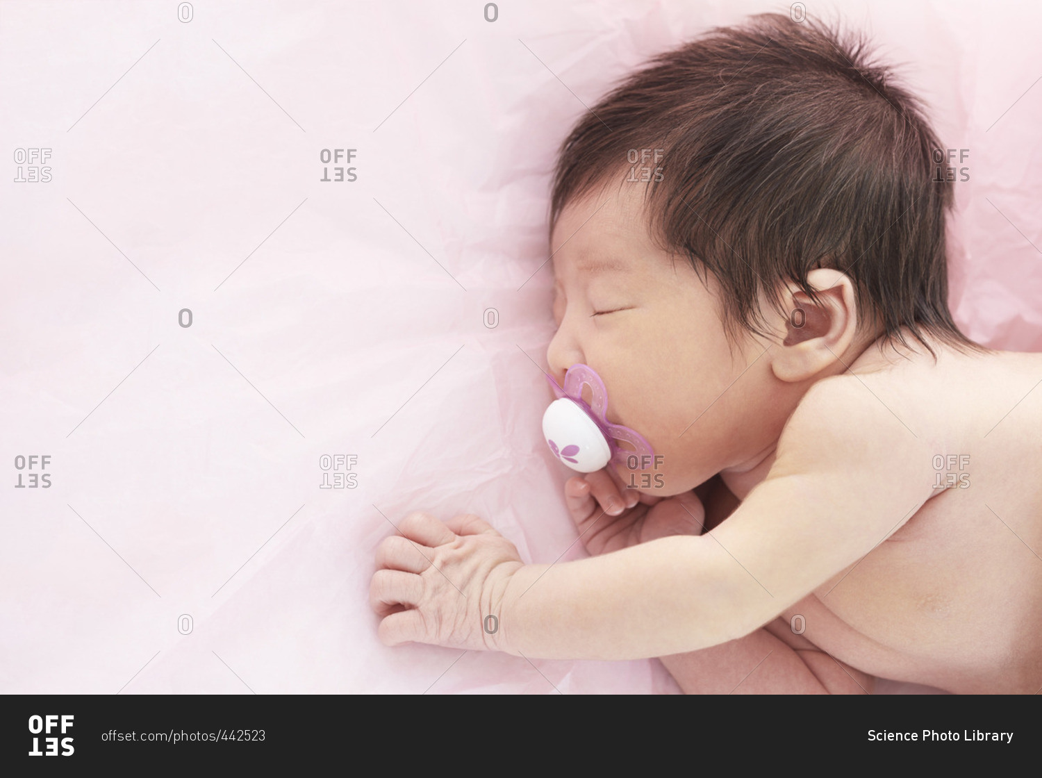 Newborn baby girl with dummy in mouth