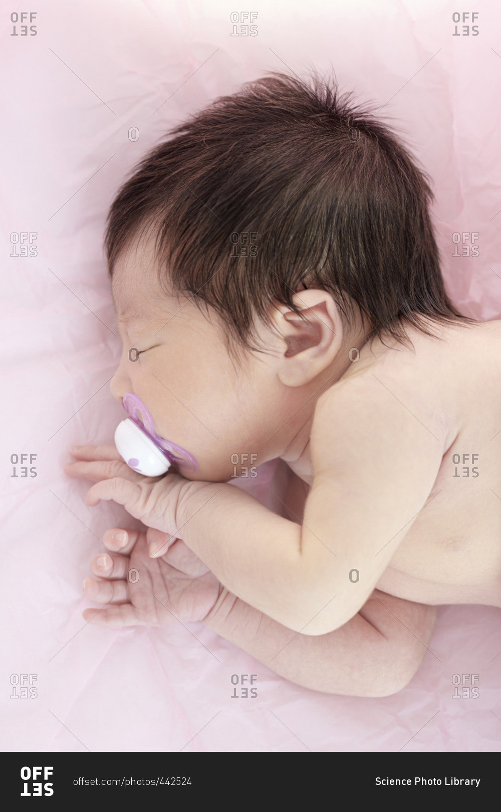 Newborn baby girl with dummy in mouth