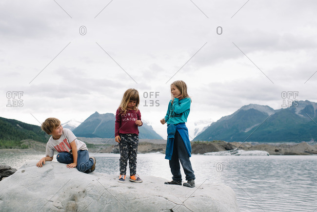 Children sitting on a rocky outcropping in the Alaskan wilderness