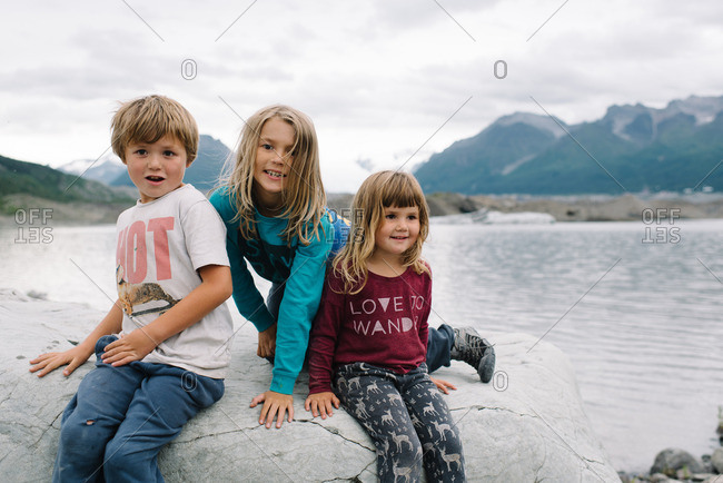 Children sitting together on a rocky outcropping in the Alaskan wilderness