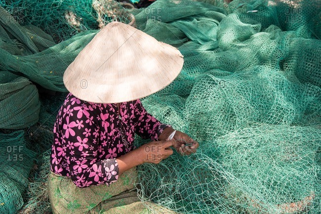 Vietnamese woman stitching fishing net