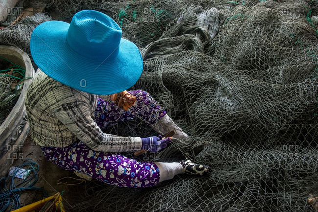 Vietnamese woman repairing fishing net