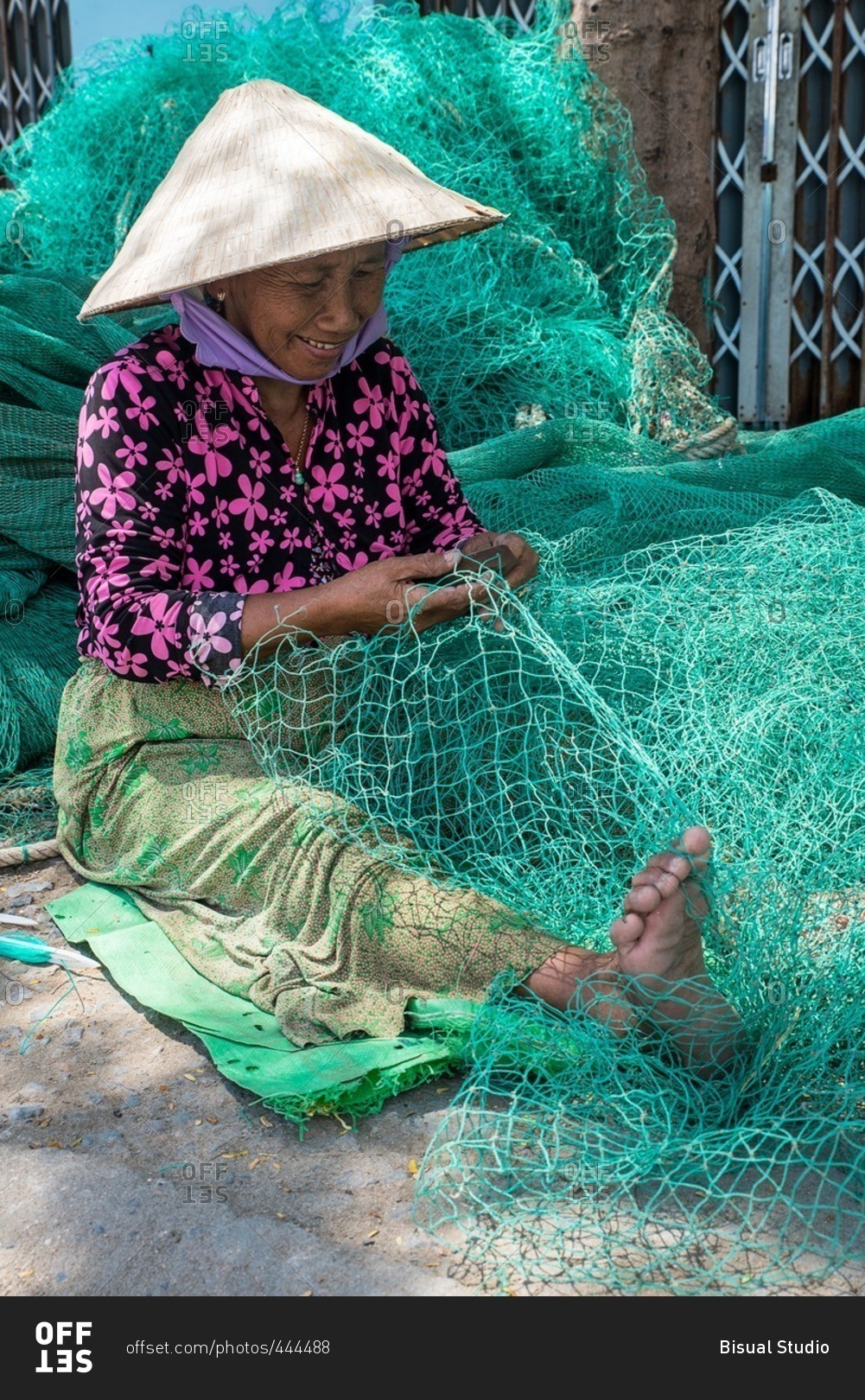 Woman repairing fishing net stock photo 