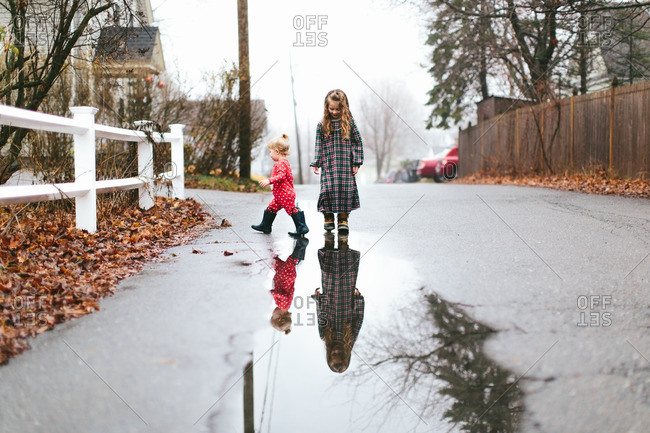 Sisters in pajamas playing in puddles