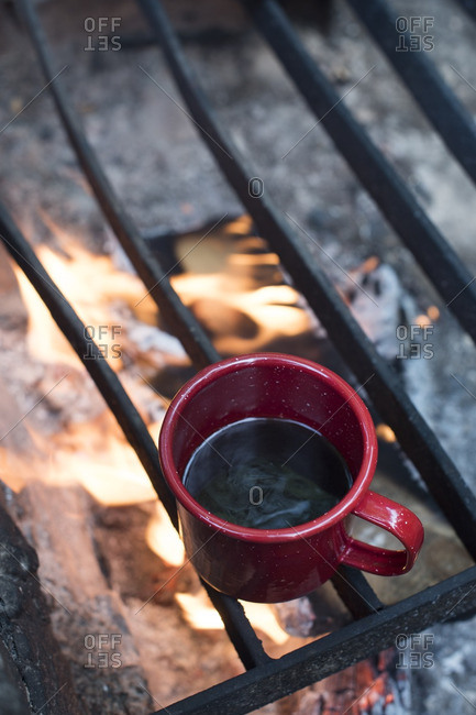 Heating cup of coffee on campfire