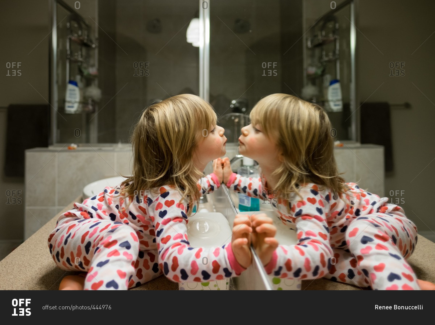 Little girl kissing herself in the bathroom mirror