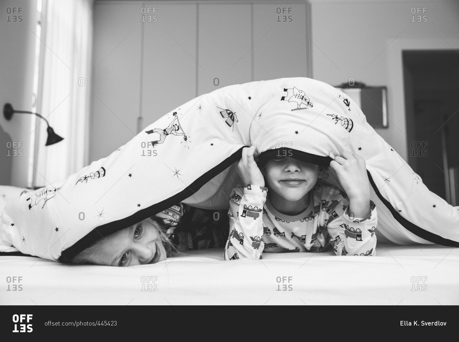 Two kids hiding under blanket stock photo OFFSET