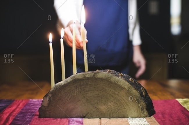 Woman lighting a fifth candle on a menorah made from a log