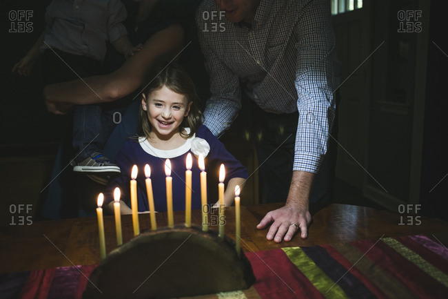Family standing at a table admiring a menorah made from a log