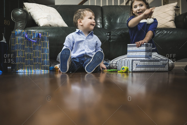 Boy and girl sitting on a living room floor opening gifts for Hanukkah