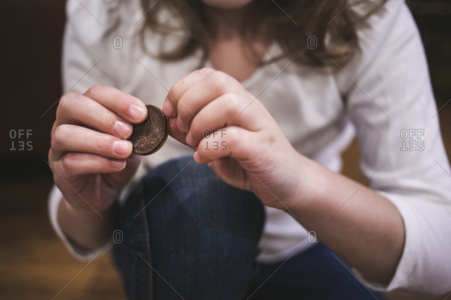 Little girl unwrapping a chocolate gelt coin