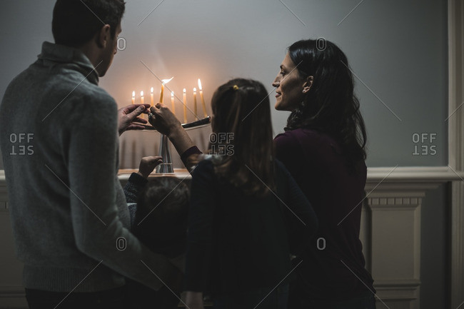 Family lighting a menorah on a fireplace mantle
