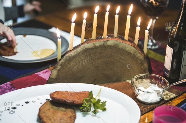 Platter of latkes and a lighted menorah on a dining table