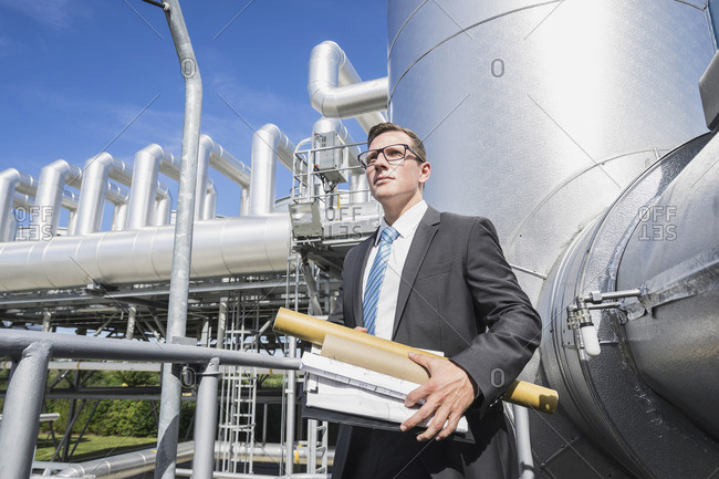 Young businessman standing with his arms crossed at geothermal power station, Bavaria, Germany