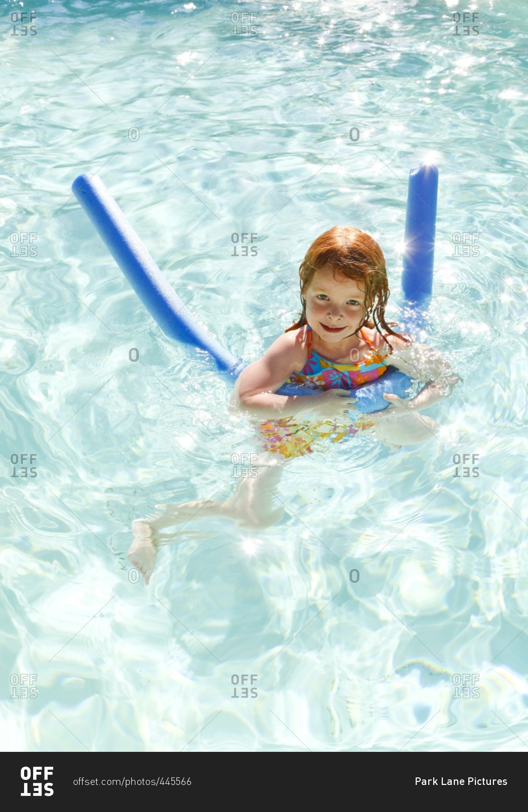 A little girl swimming in a swimming pool with a float.