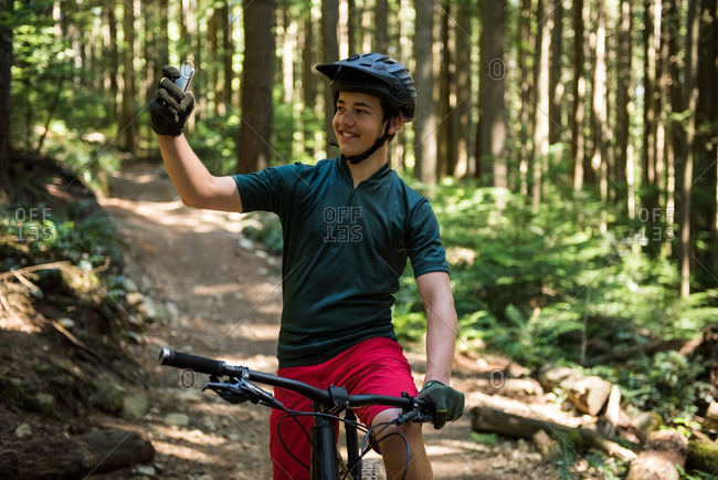 Male cyclist taking selfie on mobile phone in forest