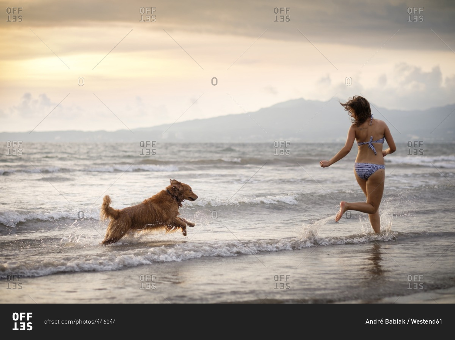 Mexico- Nayarit- Young woman in bikini playing with her Golden Retriever dog at the beach