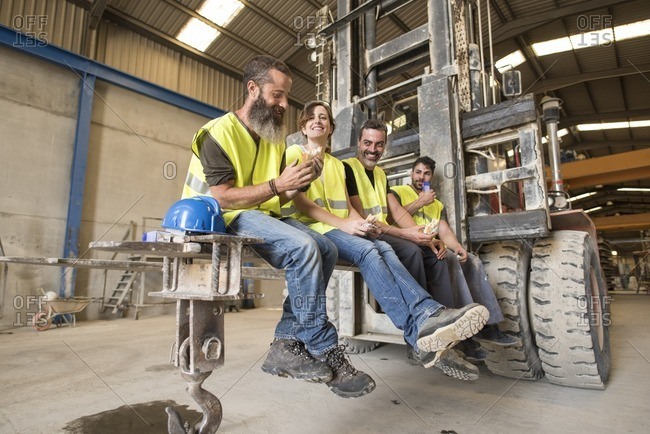 Workers having lunch on the shovel of a giant forklift
