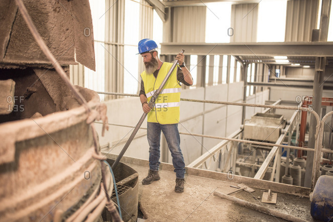 Man working in factory hall at giant concrete mixer