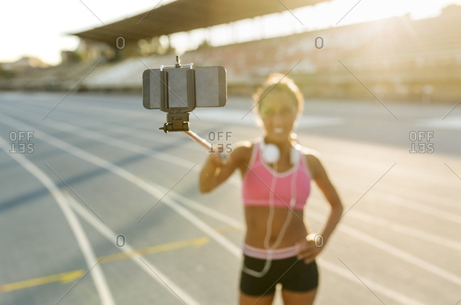 Female athlete taking selfies in stadium- holding selfie stick