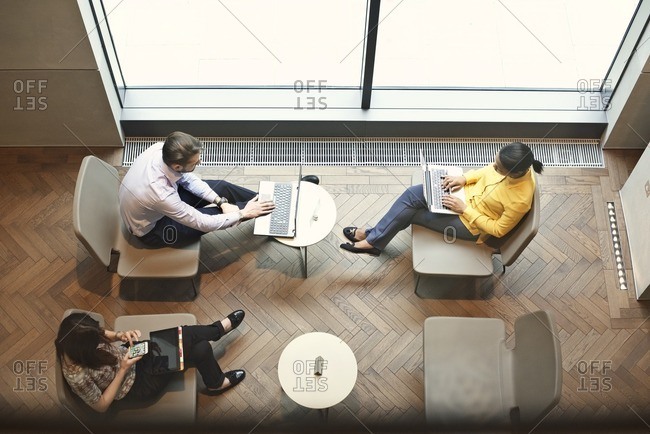 Office workers using devices in sitting area