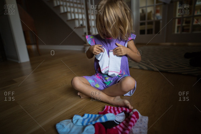 Girl holding a matching pair of ankle socks in the living room