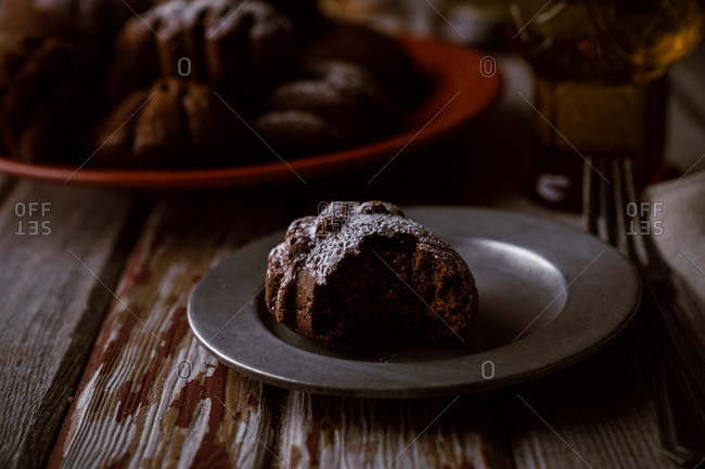 Half-eaten chocolate acorn cake on plate with powdered sugar