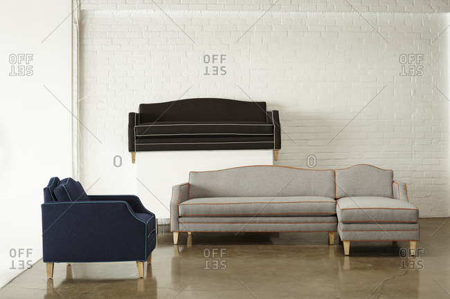 Sofas with contrasting piping on display in front of a painted brick wall