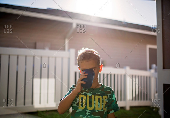 Boy drinking from cup outside