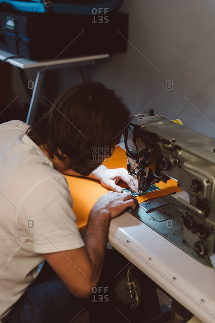 Entrepreneur sewing fabric patch onto orange cloth on a sewing machine