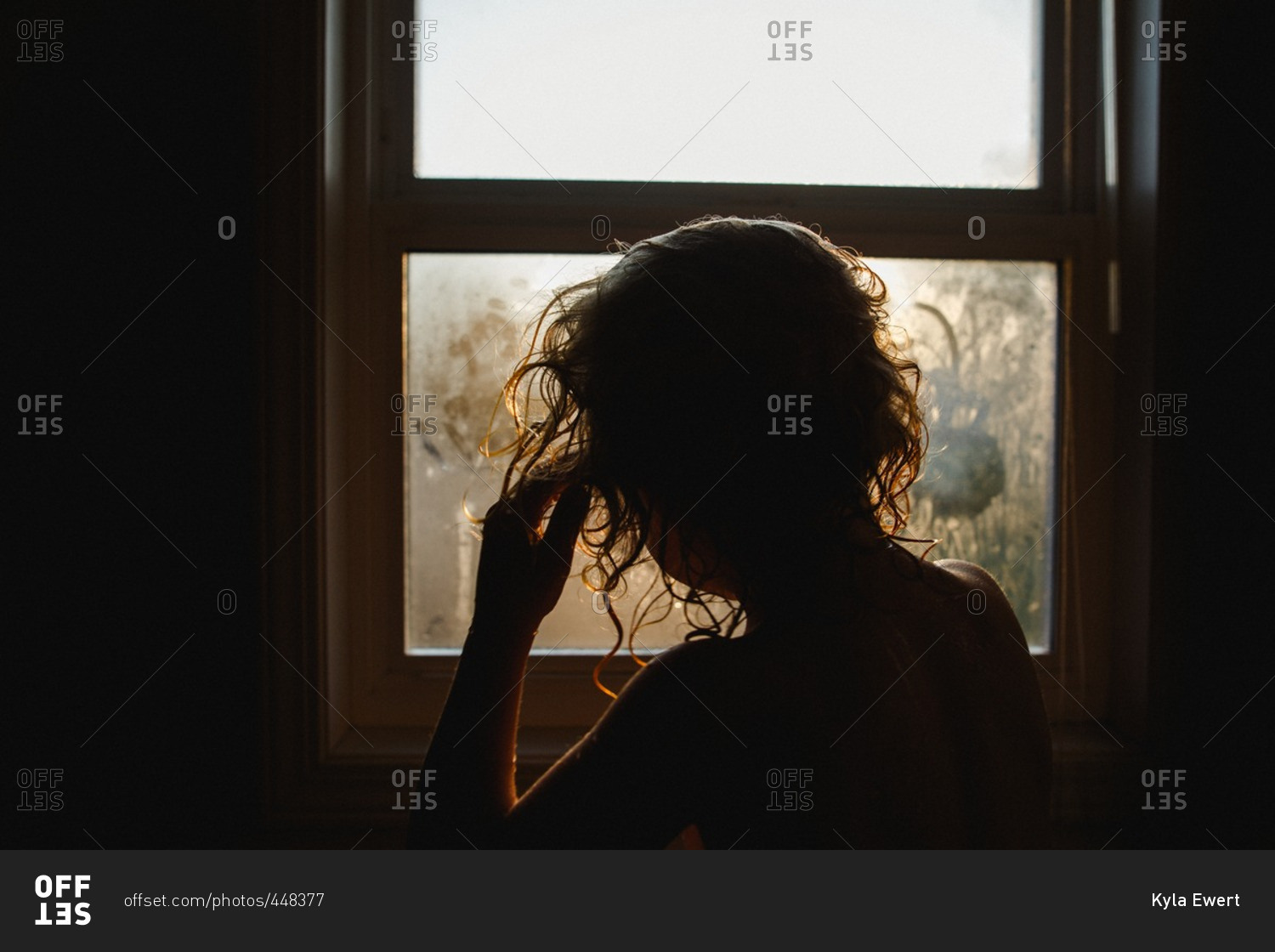 Child with wet hair looking out a fogged window