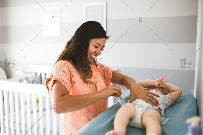 Woman changing her toddler son on a changing table