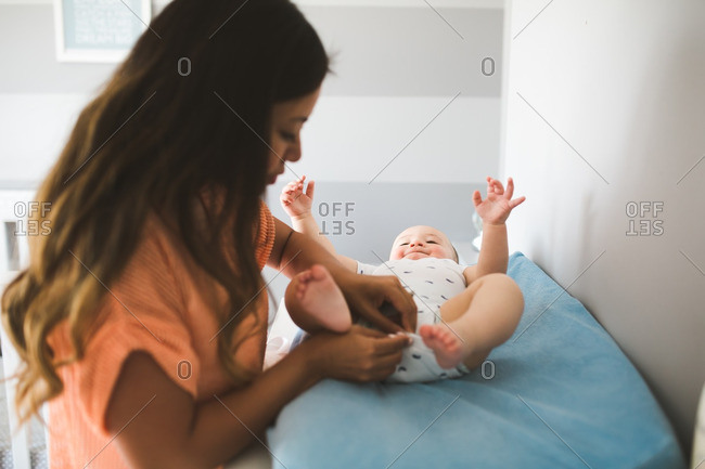 Mother changing her baby son on a changing table