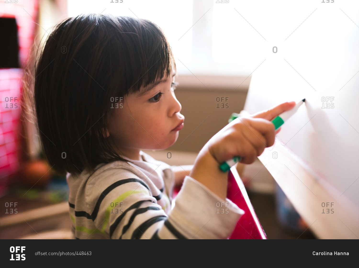 Little boy drawing on a dry erase easel in a playroom